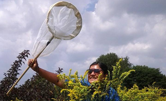 Abi Saeed holding a butterfly net behind a bush